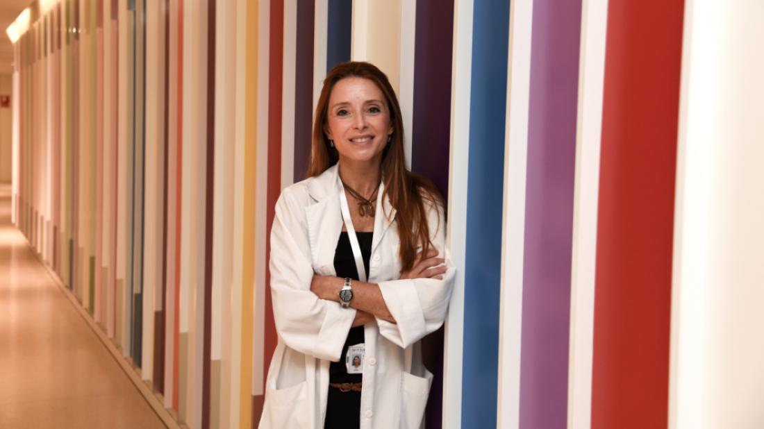 Retrato de Iolanda Jordan en un pasillo del Hospital Sant Joan de Déu Barcelona con un mural de franjas multicolor al fondo.